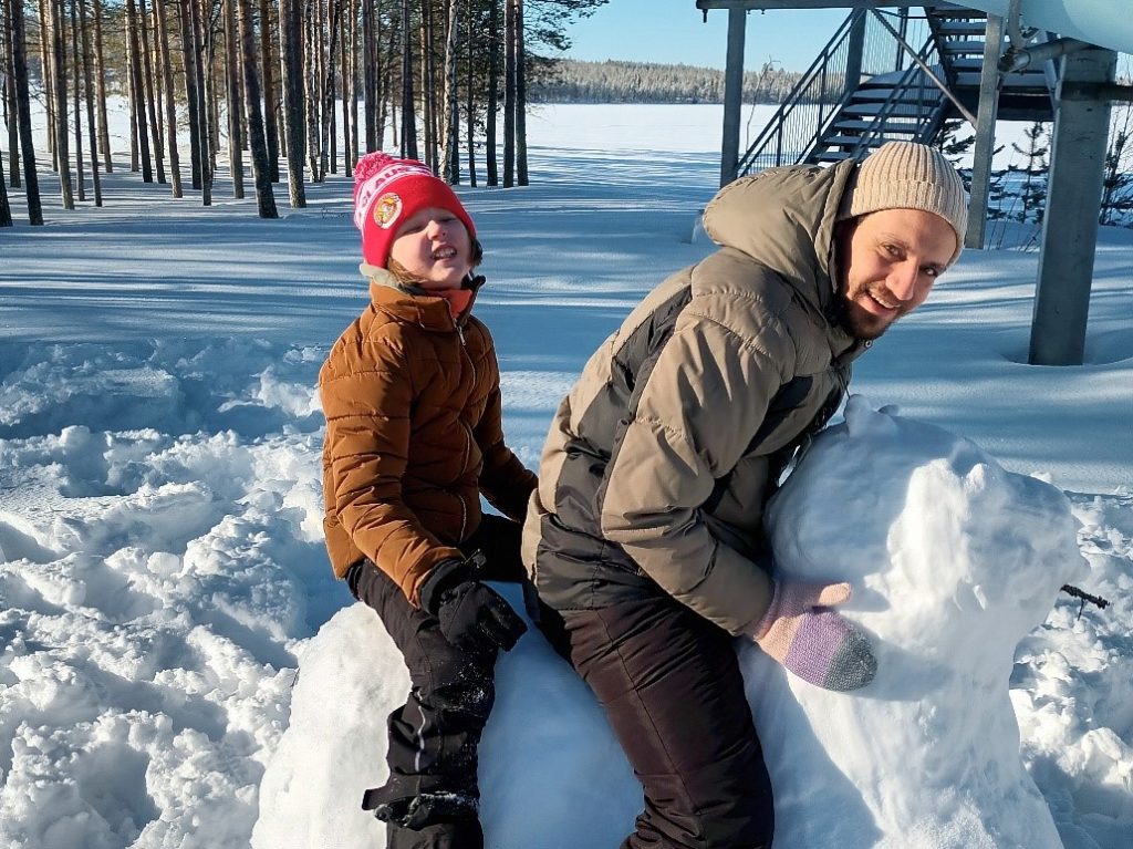 Lapsi ja ohjaaja ratsastavat lumihevosella