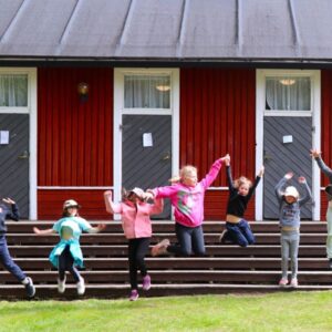 Lapset pomppaavat ilmaan Koivuhaan leirikeskuksen aittojen edessä