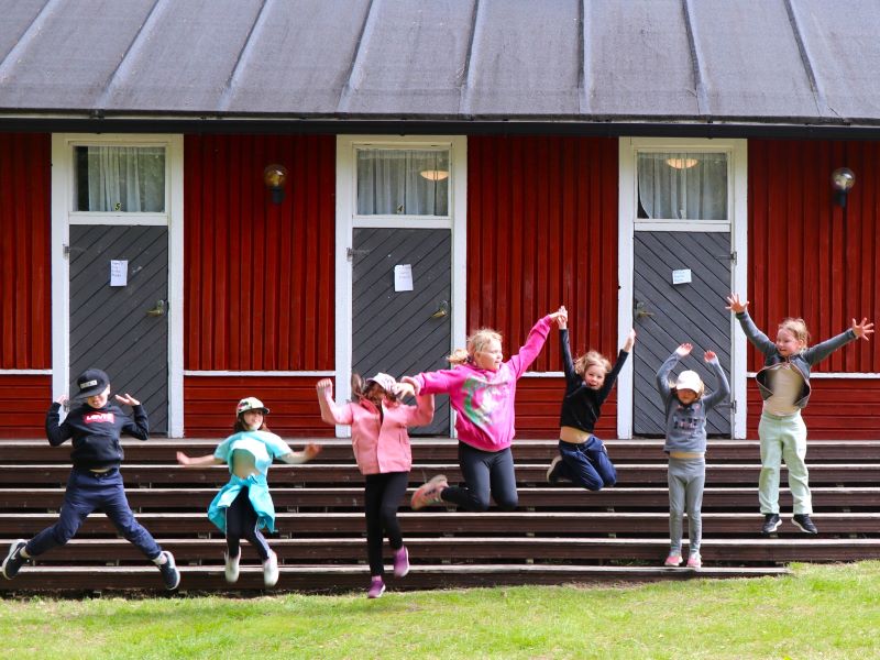 Lapset pomppaavat ilmaan Koivuhaan leirikeskuksen aittojen edessä