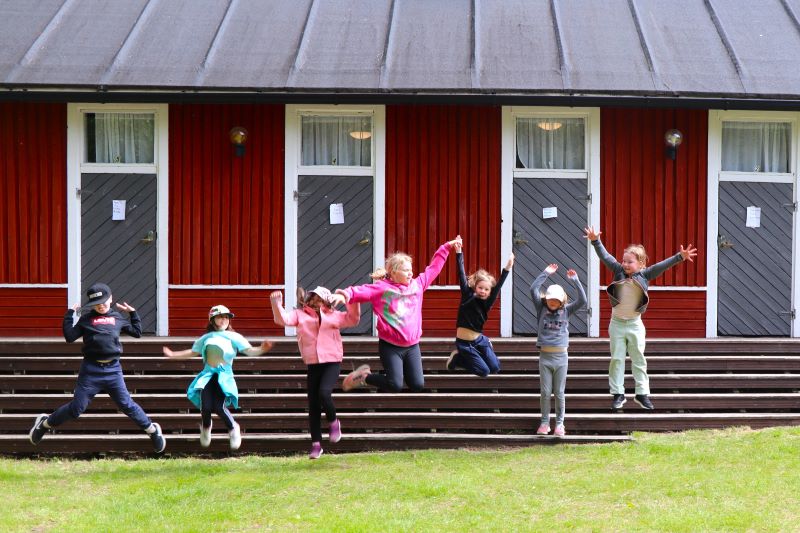 Lapset pomppaavat ilmaan Koivuhaan leirikeskuksen aittojen edessä