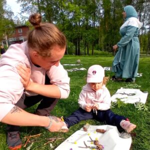Isä ja lapsi perheleirillä askartelevat nurmikolla