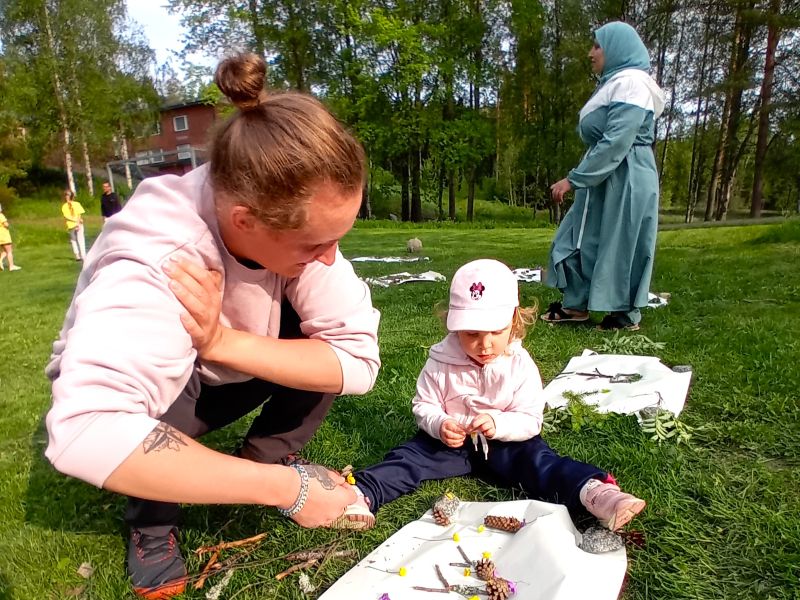 Isä ja lapsi perheleirillä askartelevat nurmikolla
