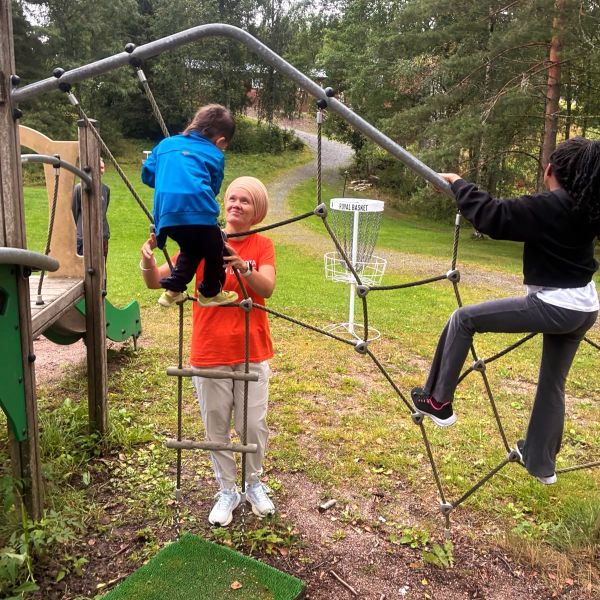 Leiriohjaaja auttamassa lapsia kiipeilemään
