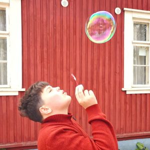 Poika puhaltaa saippuakuplan leirillä