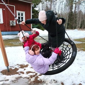 Kolme lasta keinussa leirillä