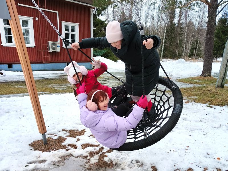Kolme lasta keinussa leirillä
